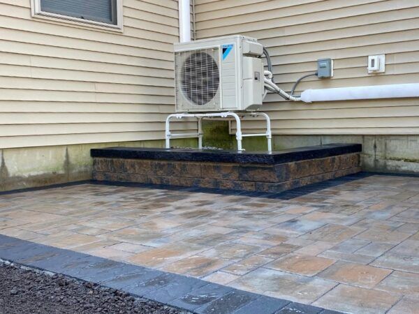 A large air conditioner is sitting on the side of a house.