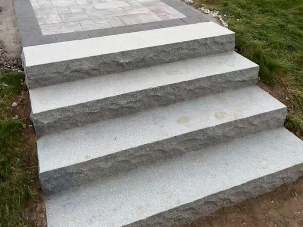 A set of stone stairs leading up to a grassy area.