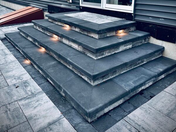 A set of stairs leading up to a house with lights on them.