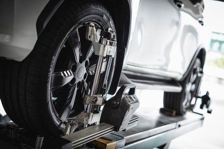 A car is being adjusted on a lift in a garage.