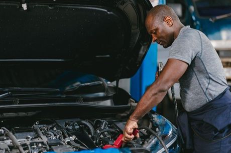 A man is working on the engine of a car in a garage.