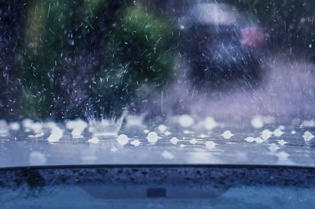 Hail is falling on a car windshield in the rain.