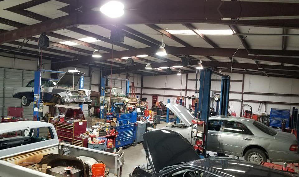 A garage filled with cars and trucks being worked on.