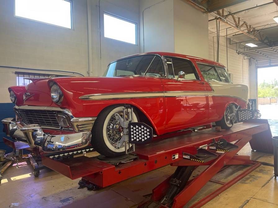 A red car is sitting on top of a red lift in a garage.