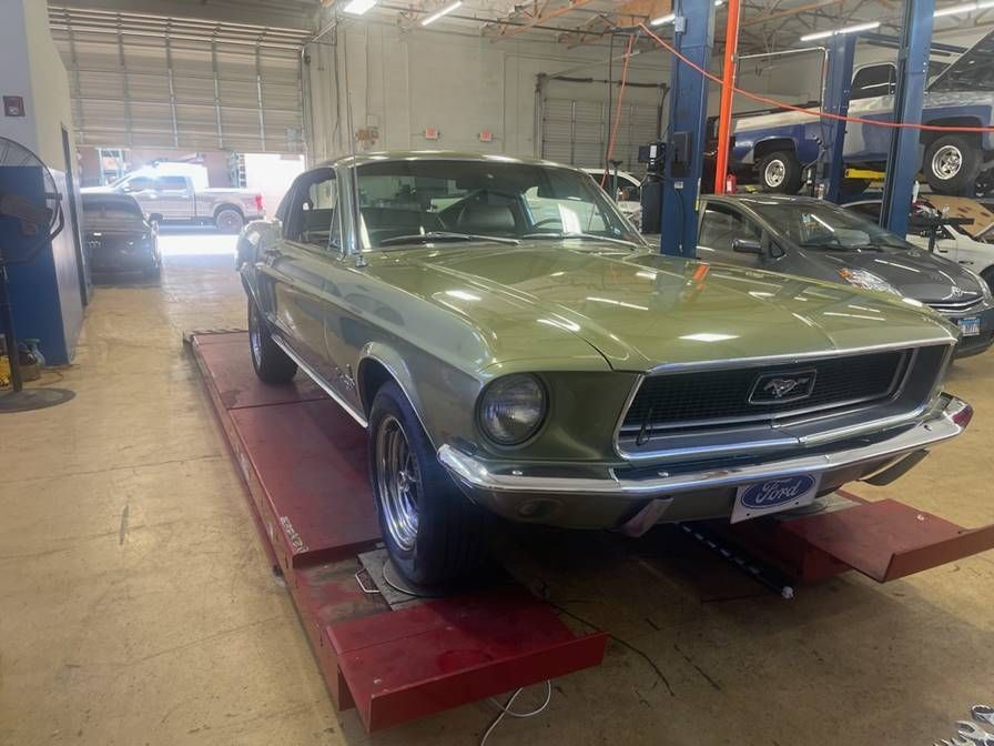A green mustang is parked on a lift in a garage.