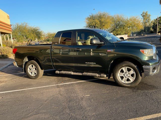 A green toyota tundra is parked in a parking lot.