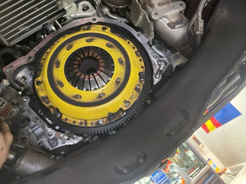 A close up of a yellow clutch on a car engine.