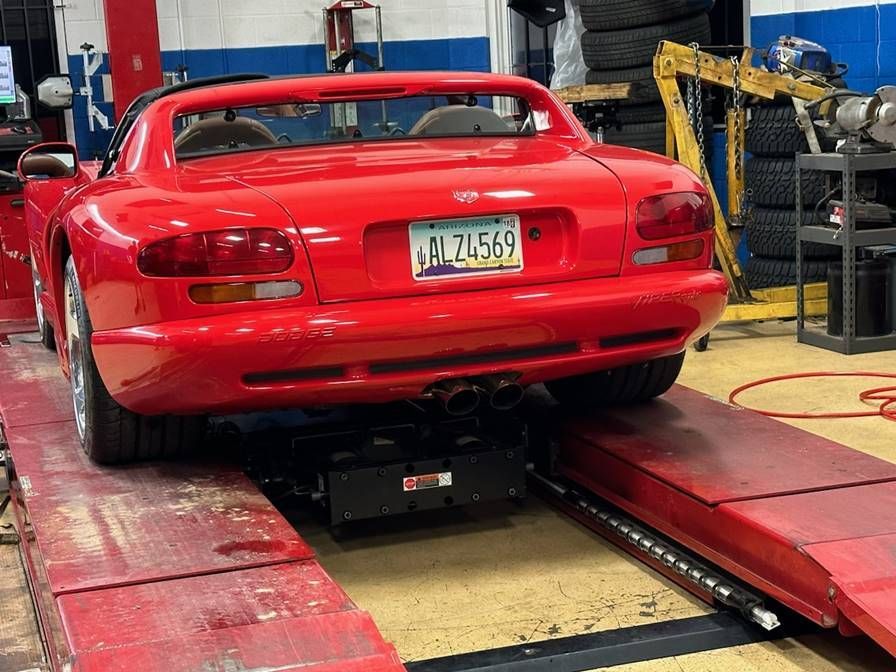 A red sports car is sitting on a lift in a garage.