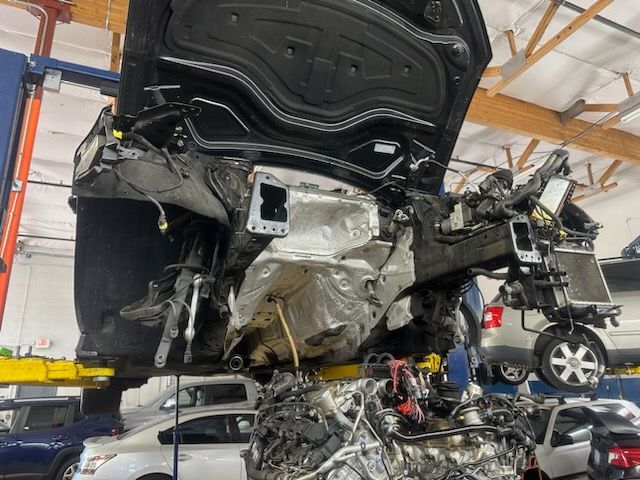 A car is being dismantled in a garage with the hood up
