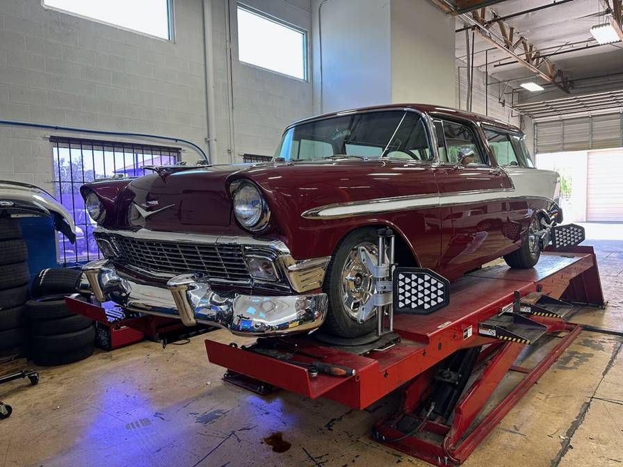 A red car is sitting on top of a red lift in a garage.