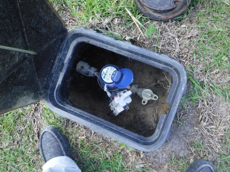 A water meter is in a black box on the ground
