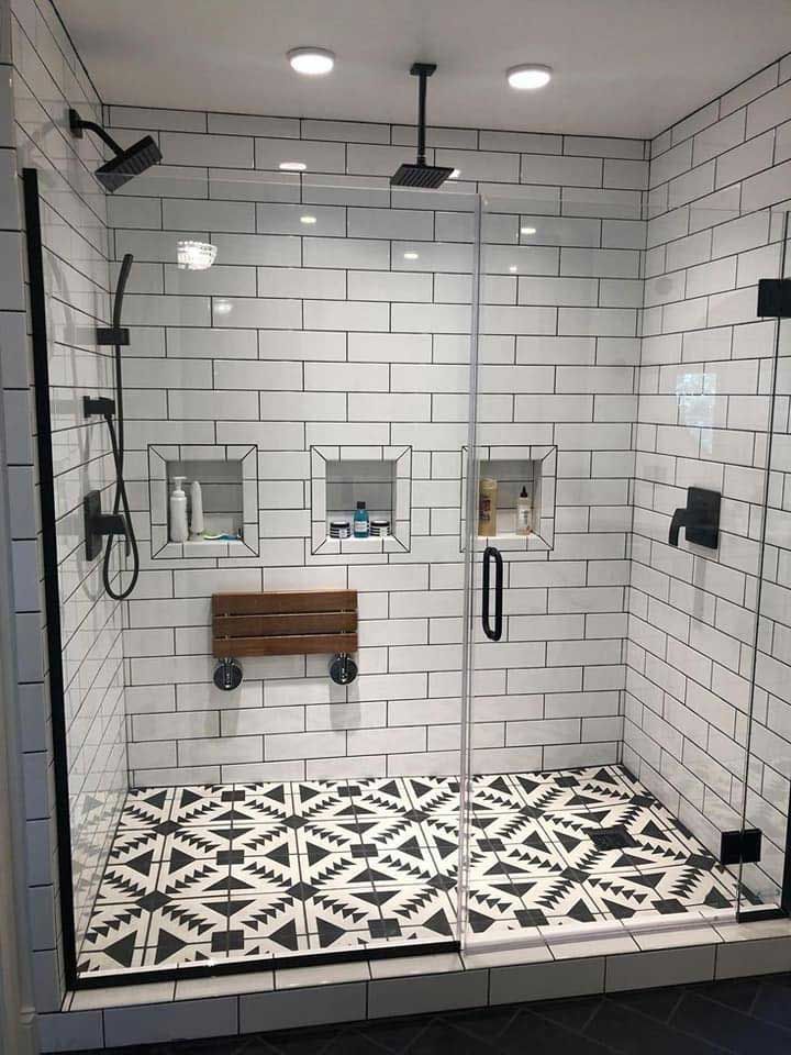 A walk-in shower with white tiles and a black and white tile floor.