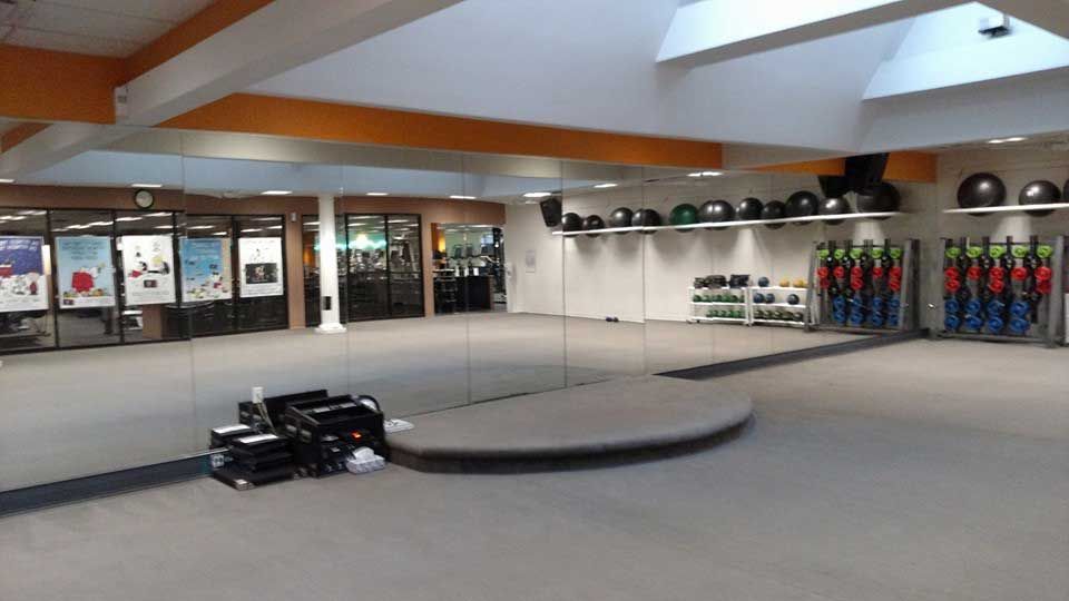 A large empty gym with a lot of mirrors and exercise balls.