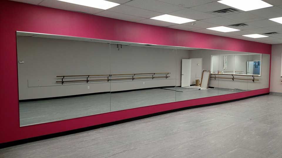 A large dance studio with a large mirror on the wall.