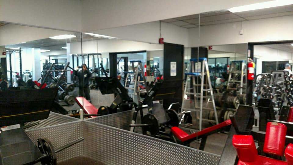 A gym with a lot of exercise equipment and mirrors