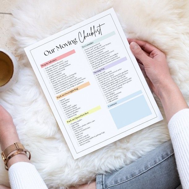 Hand holding a printed moving checklist on a white fur surface with a coffee cup nearby