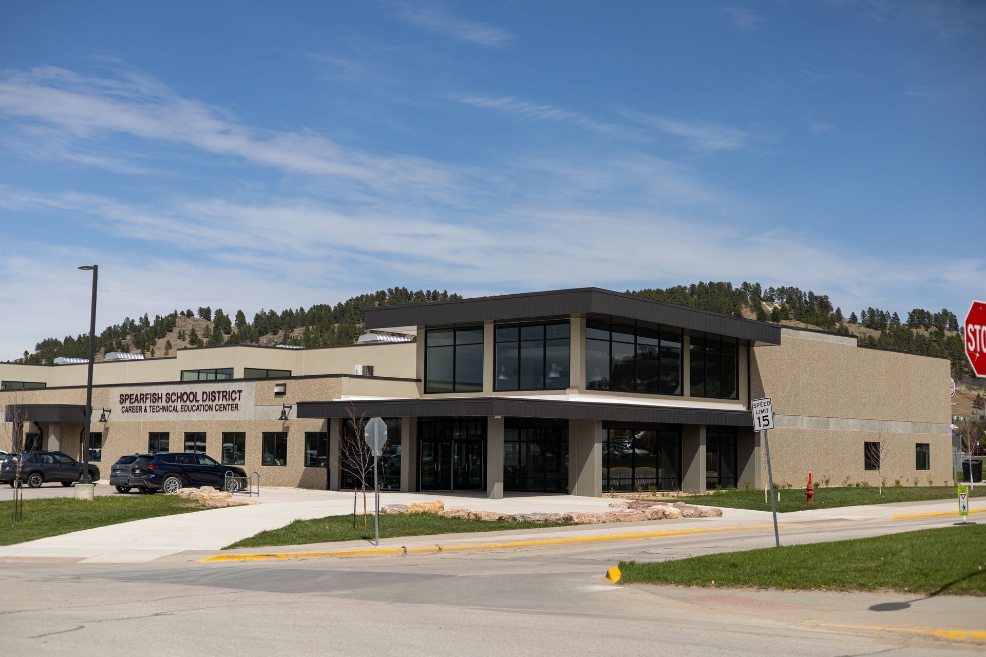 Modern, tan-colored building with large windows and a flat roof, under a blue sky, possibly a post office.