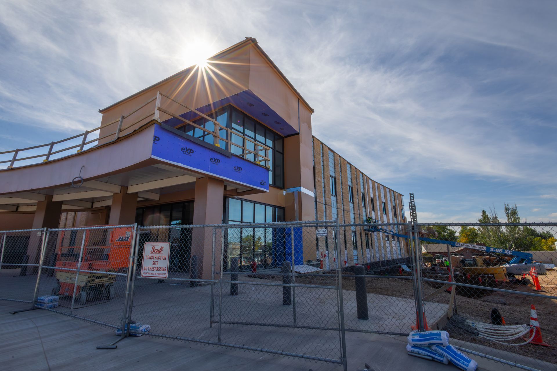 Building under construction behind a chain-link fence on a sunny day.