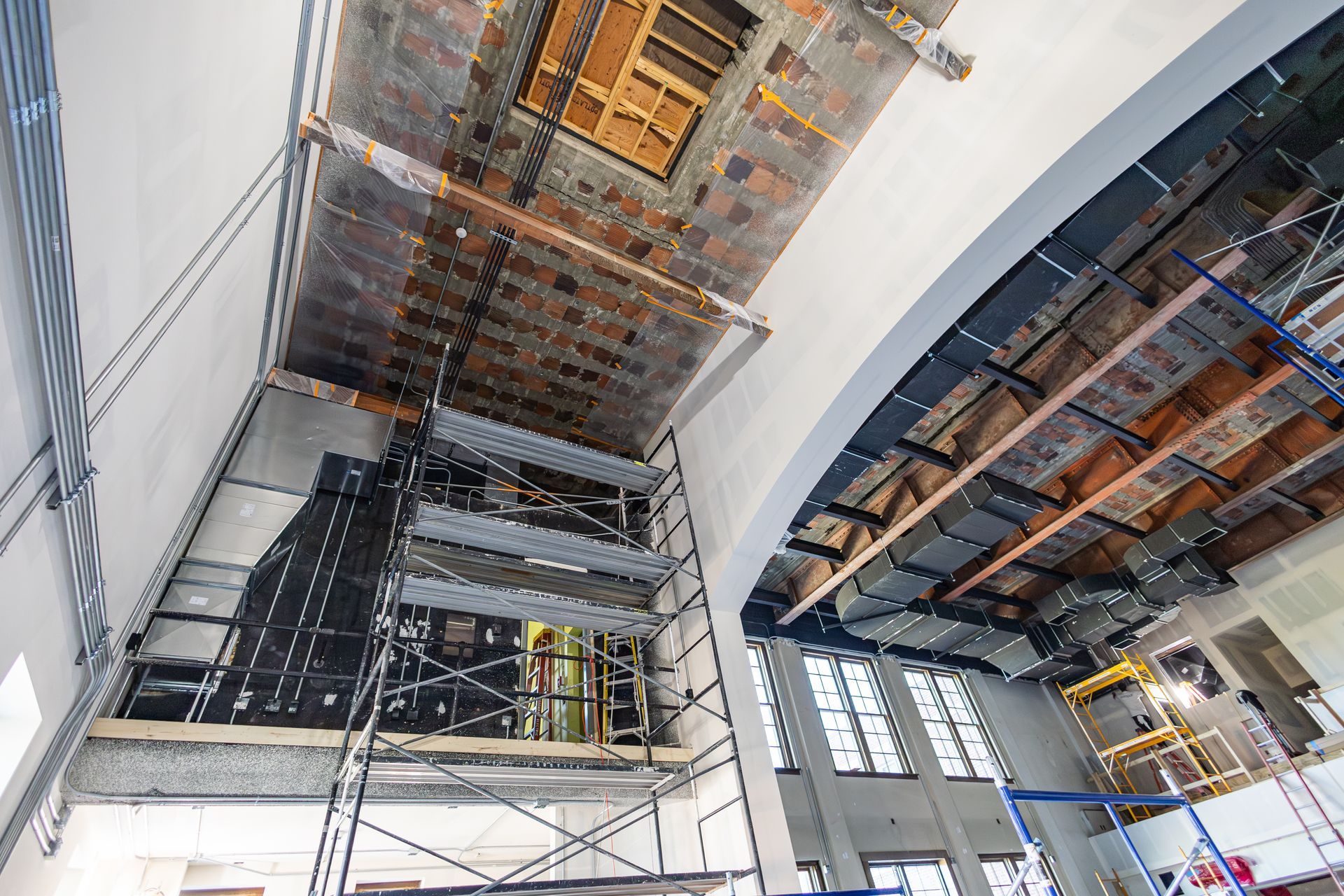 Interior view of building under construction with scaffolding and exposed ceiling.