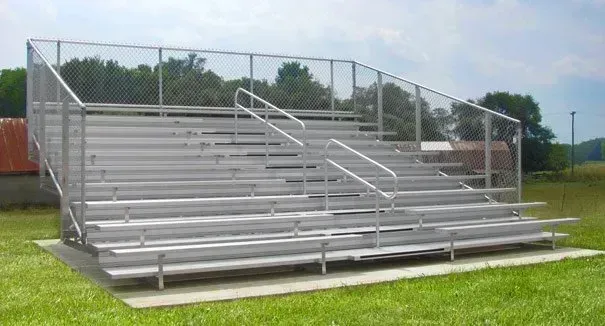 Bleacher seating with chain-link fencing, likely for a sports field.