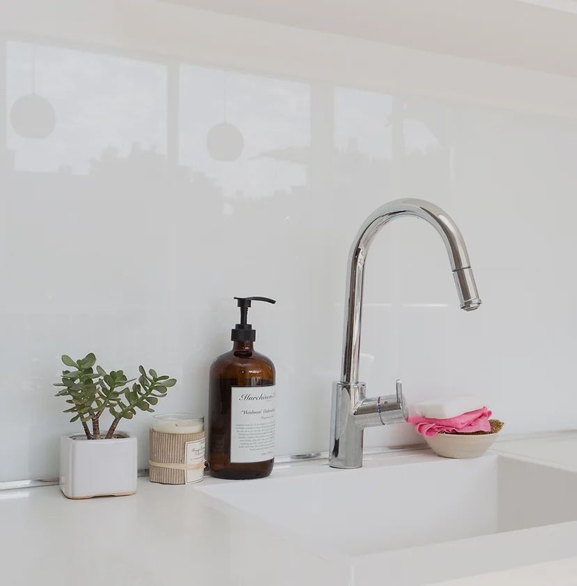 A bottle of soap sits on a counter next to a sink