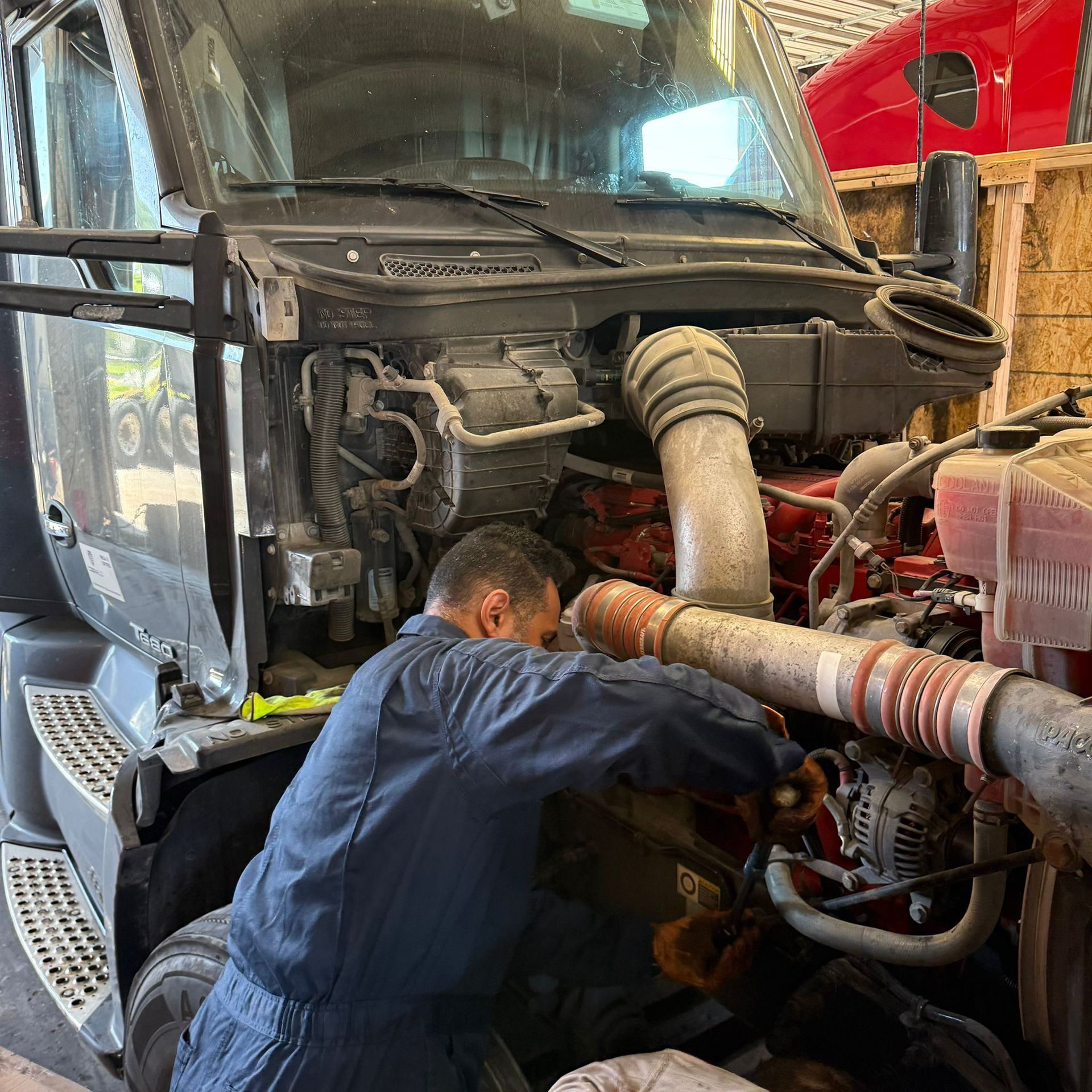 Mechanic working on the engine of a semi-truck in a garage.