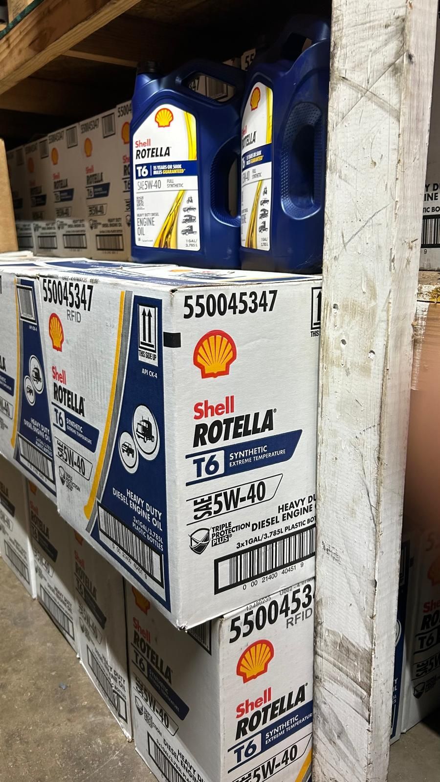 Shell Rotella T6 oil containers and boxes in a storage area. Blue and white branding is visible.