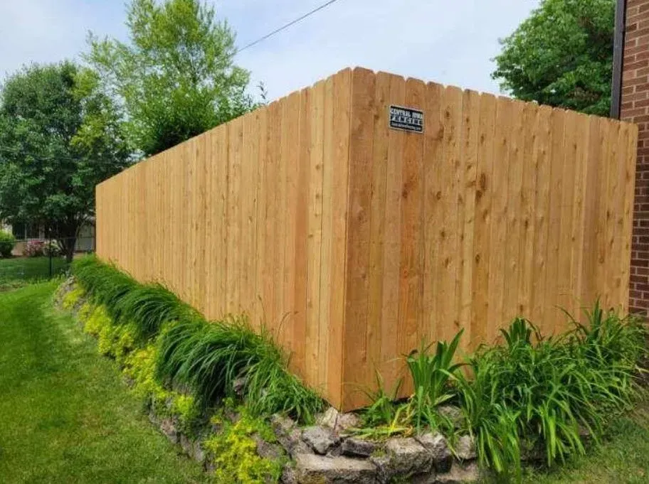 Wooden fence surrounding a yard with green grass and foliage.