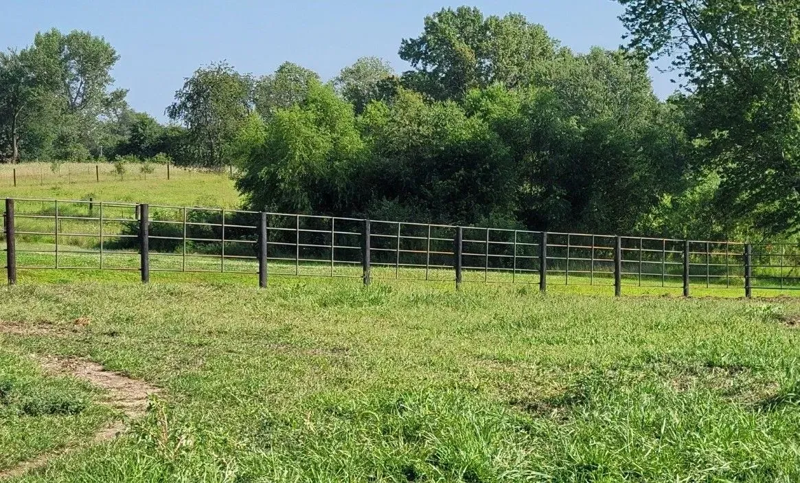 A series of dark posts in a grassy field form the word 