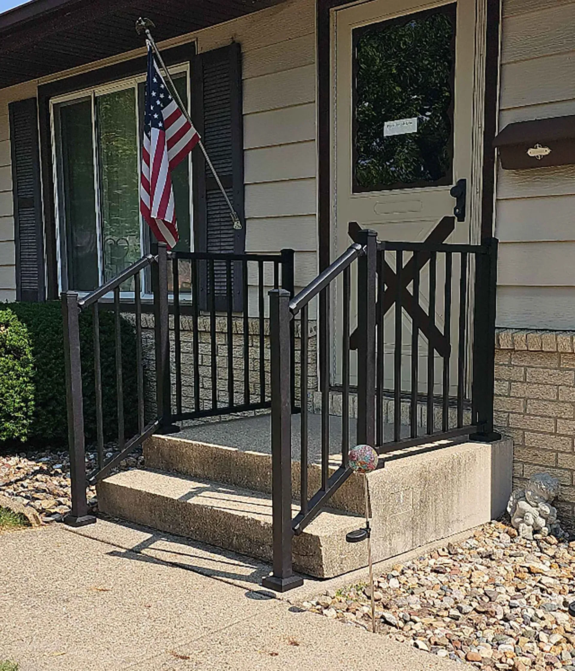 Concrete porch with black railing and American flag.