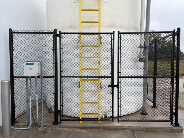 Chain-link fence around industrial tank with a yellow ladder