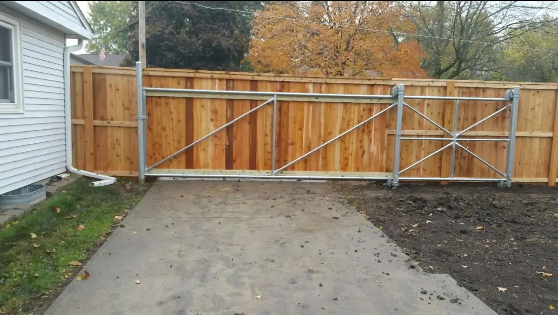 Wooden fence with metal gate in a driveway.