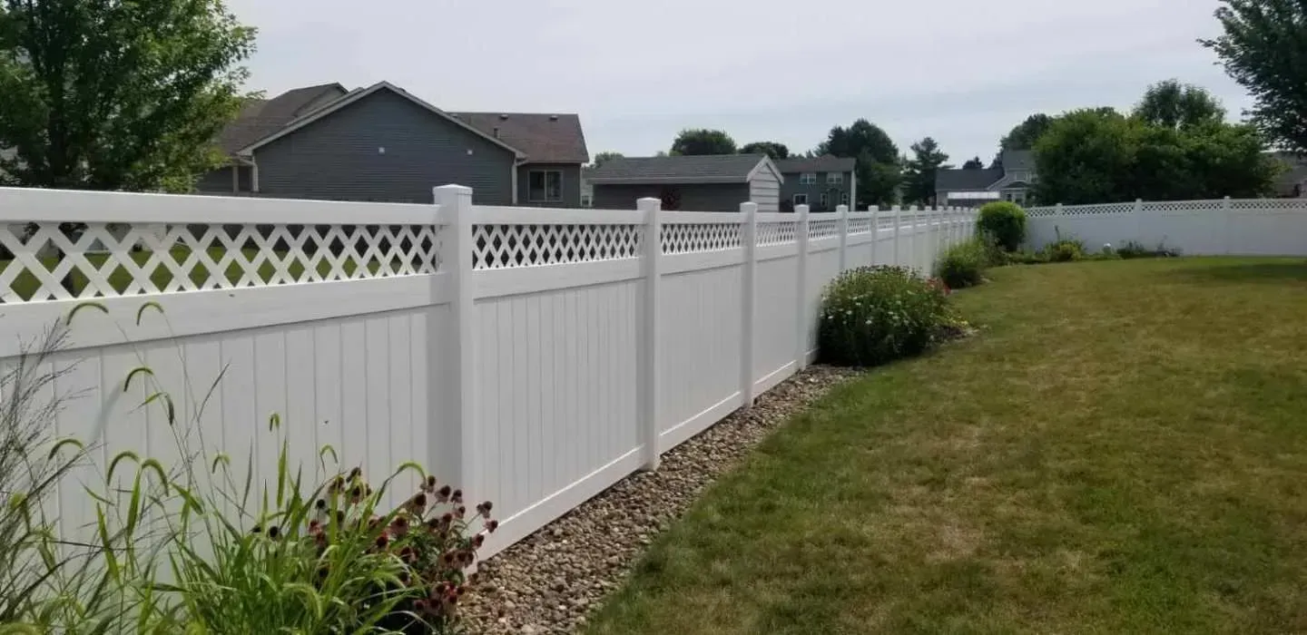 White vinyl fence with lattice top, surrounding a grassy backyard with houses in the background.