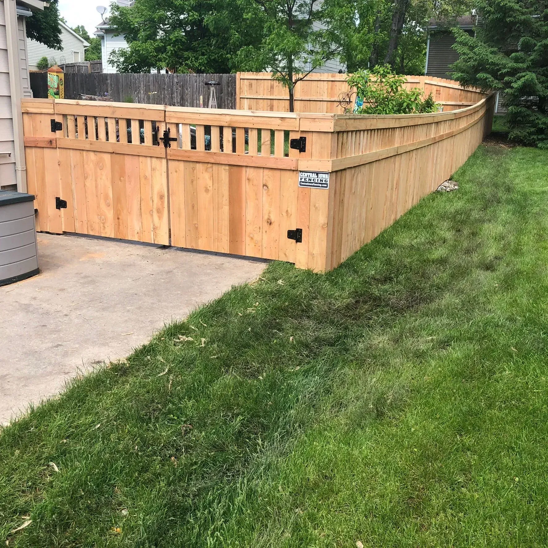 Wooden fence along a green lawn and concrete patio.