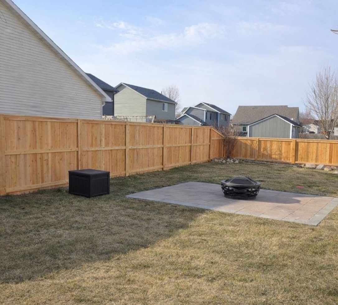 A backyard with a light-colored wood fence