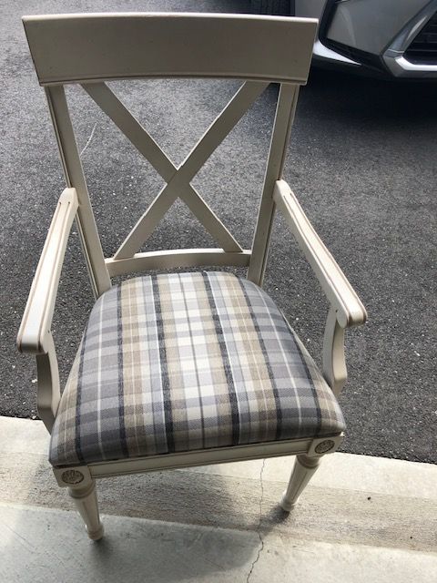 A chair with a plaid cushion is sitting in front of a car.