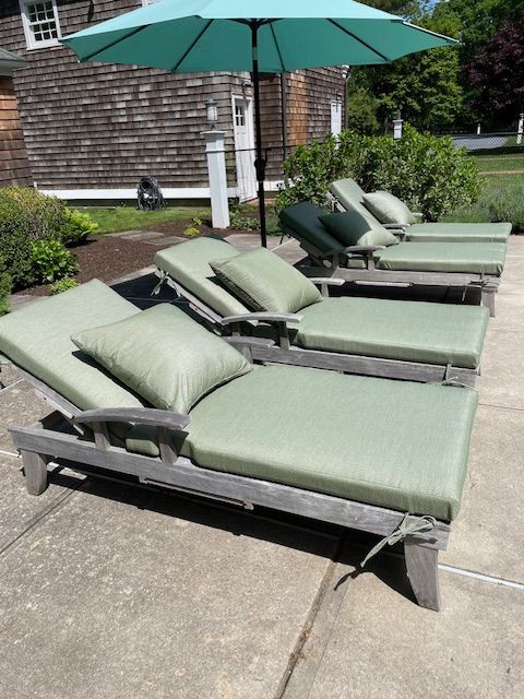 A row of green lounge chairs under an umbrella