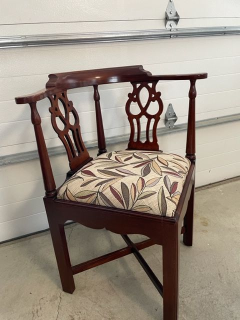 A wooden chair with a floral cushion sits in front of a garage door