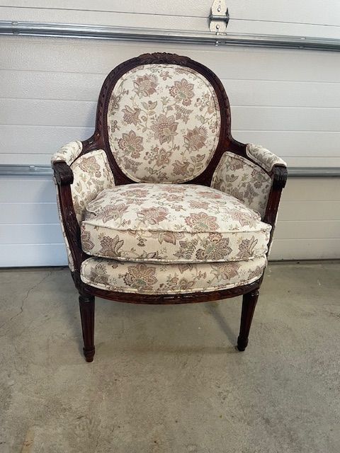 A chair with a floral pattern is sitting in front of a garage door.