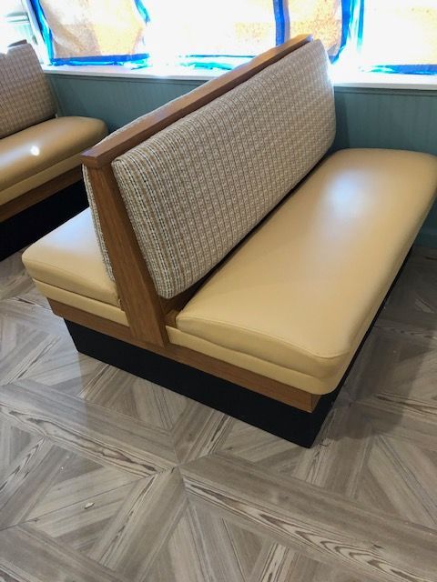 A restaurant booth with a wooden frame and a yellow cushion