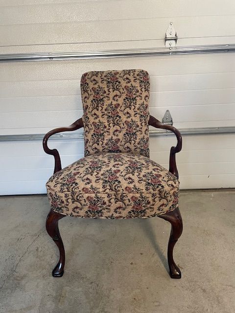 A chair with a floral pattern sits in front of a garage door