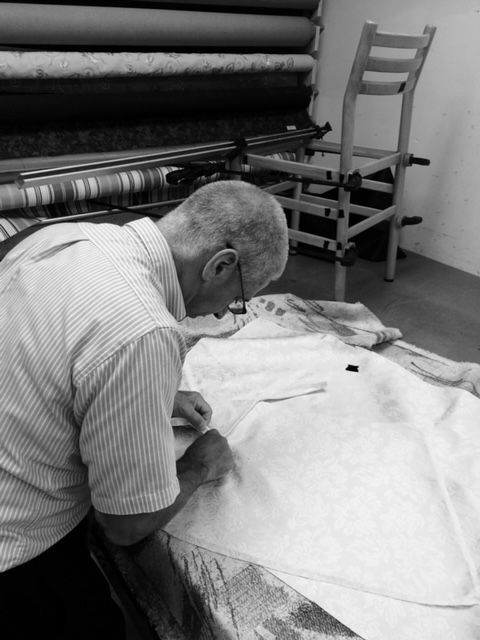 A man is working on a piece of fabric in a black and white photo