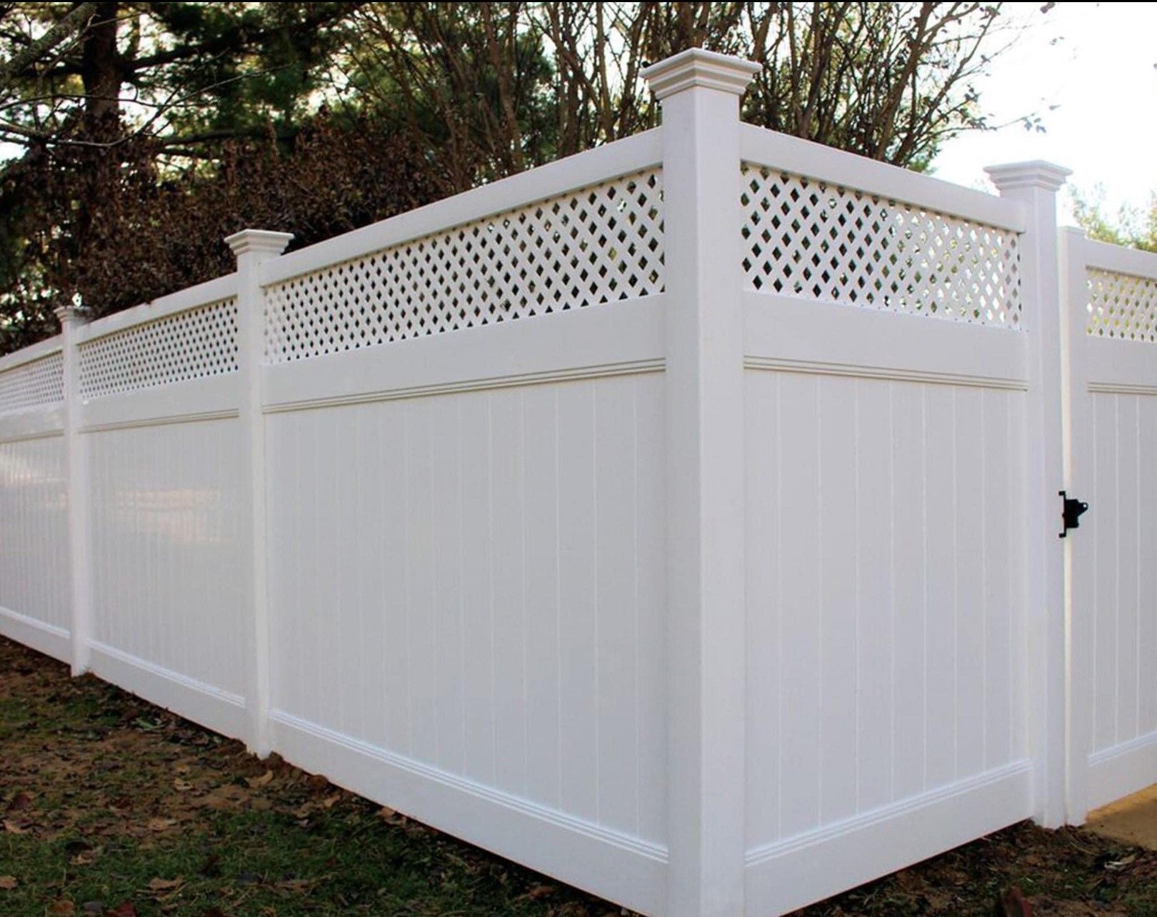 A white fence with a lattice design and a gate