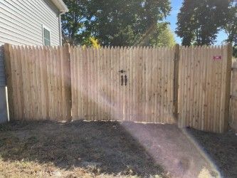 A wooden fence with a gate in the backyard of a house.