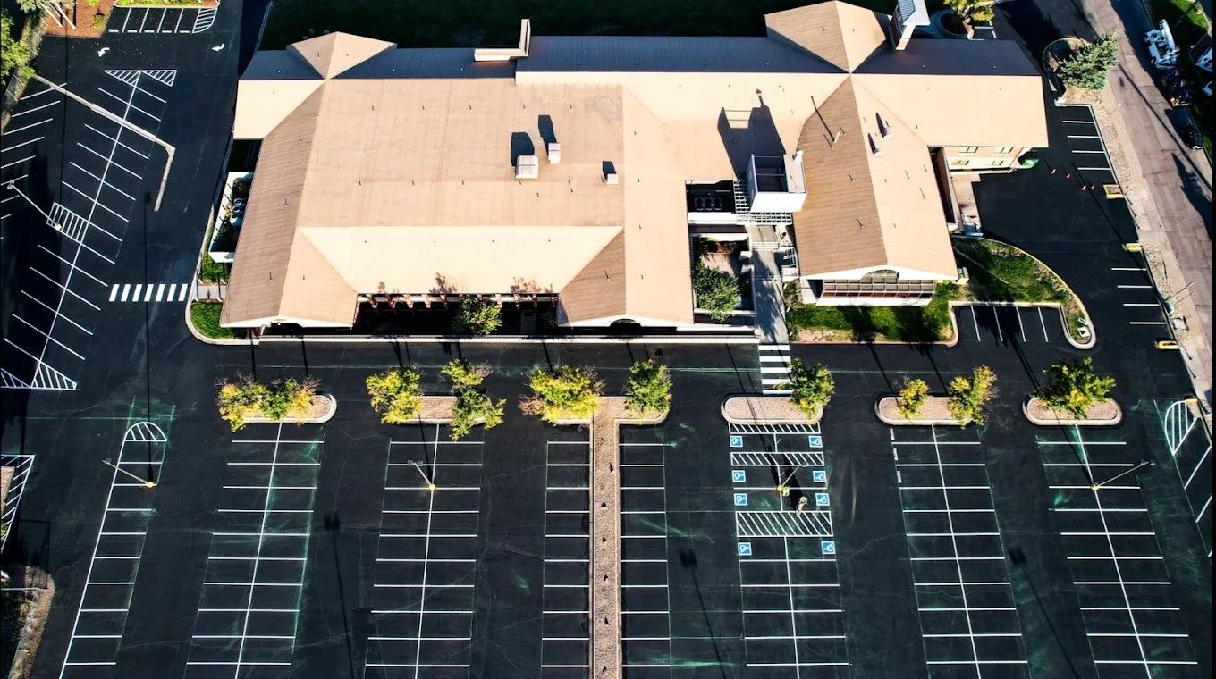An aerial view of a parking lot with a building in the background