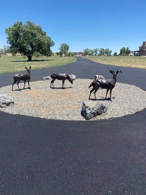 Three statues of deer in a circle on the side of a road