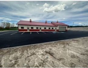 A large building with a red roof and a parking lot in front of it.