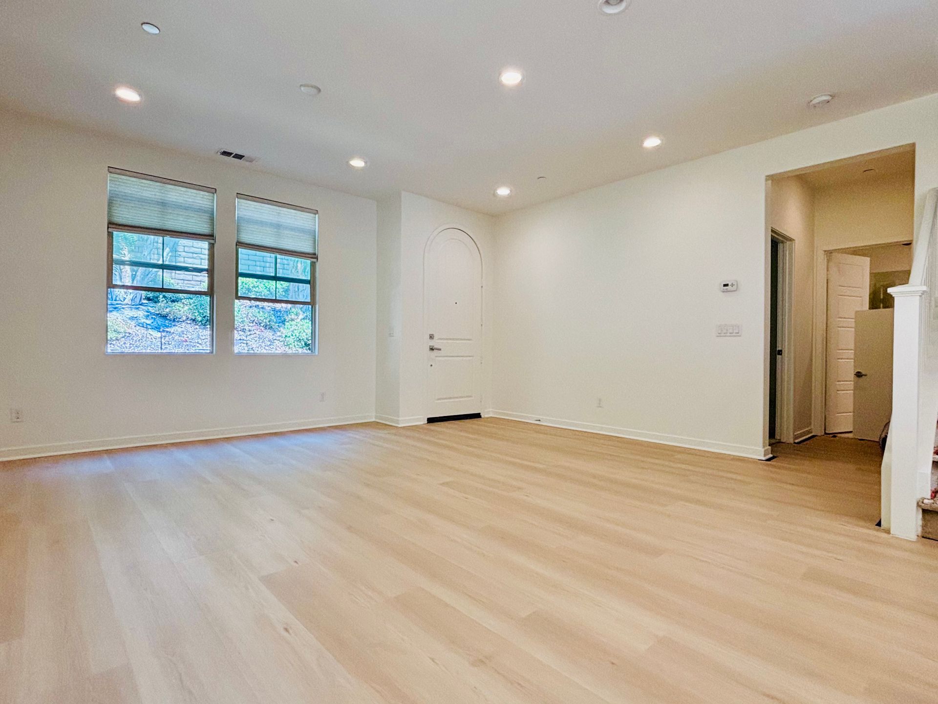 An empty living room with hardwood floors and white walls.