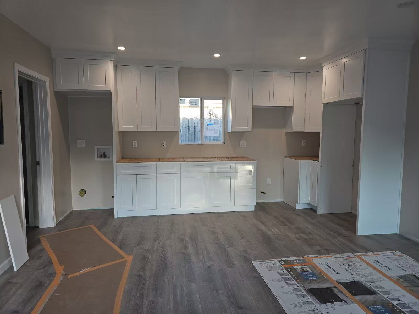 A kitchen with white cabinets and hardwood floors is being remodeled.