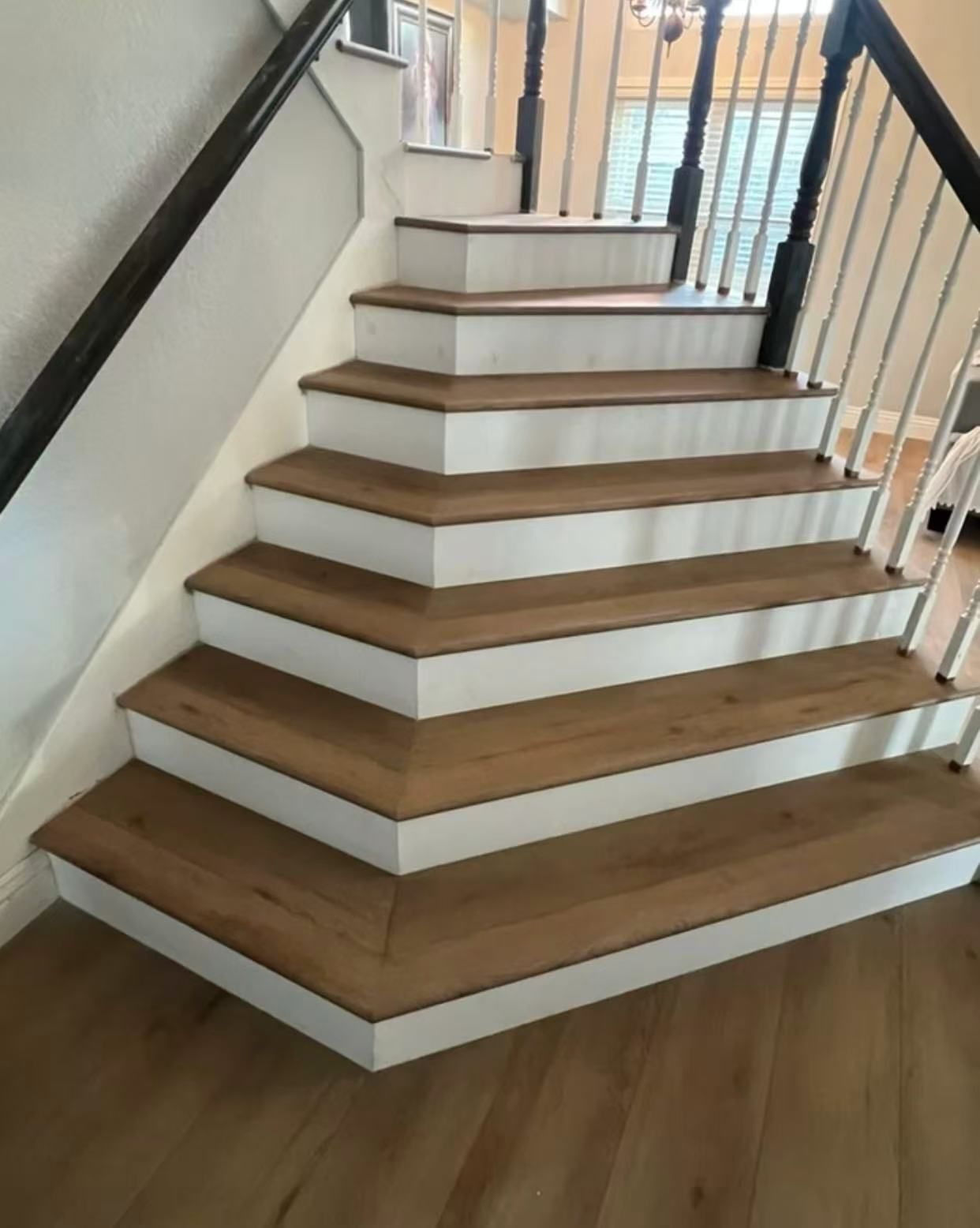 A wooden staircase with white steps and a black railing
